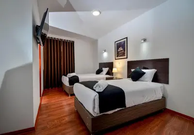 a hotel room with two beds and a flat screen tv at Ankawa Hotel Boutique in Cusco