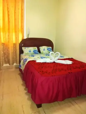 a bed with a red blanket and a white bow on it at Hotel Mandarin in Lima