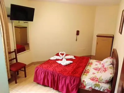 a small room with a bed with a red blanket at Hotel Mandarin in Lima
