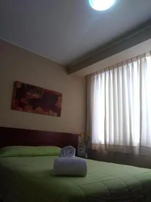 a bedroom with a green bed and a window at Hotel Sumaq Inn Sac in Lima