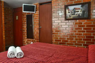 a bedroom with a brick wall and a bed with towels at Hotel Esperanza in Lima