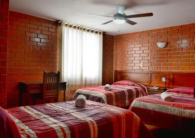 a room with two beds and a brick wall at Hotel Esperanza in Lima