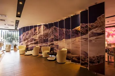 a lobby with white chairs and a wall with a mural at Arawi Miraflores Prime in Lima