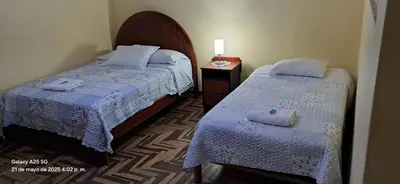 a hotel room with two beds and a night stand at Lopez House in Lima