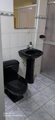 a bathroom with a black sink and a toilet at Lopez House in Lima