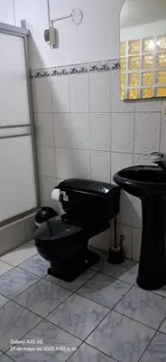 a bathroom with a black toilet and a sink at Lopez House in Lima