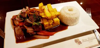 a plate of food with meat and french fries and rice at Apart Hotel San Martin in Lima