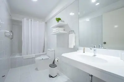 a white bathroom with a sink and a toilet at Apart Hotel San Martin in Lima