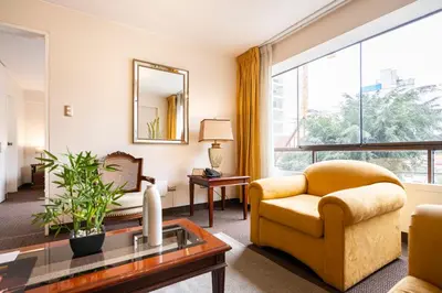 a living room with a yellow chair and a table at Apart Hotel San Martin in Lima