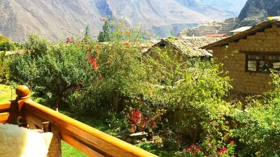 a balcony of a house with trees and flowers at Apu Lodge in Ollantaytambo