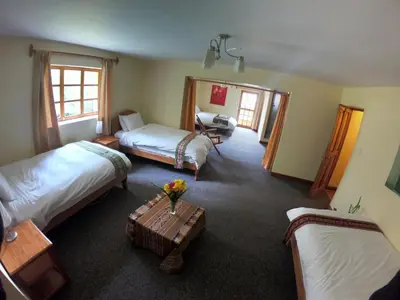 a hotel room with two beds and a table at Apu Lodge in Ollantaytambo