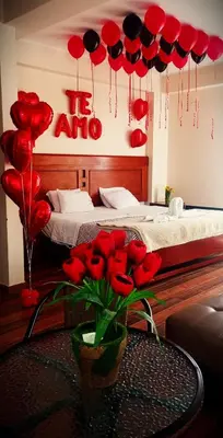 a room with a bed with red hearts and a table with roses at hotel el parral suite in Ica