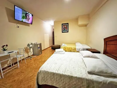 a bedroom with two beds and a flat screen tv at hotel el parral suite in Ica