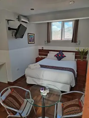 a bedroom with a bed and a glass table and chairs at HOTEL AMTALLPA San Blas Inn in Cusco