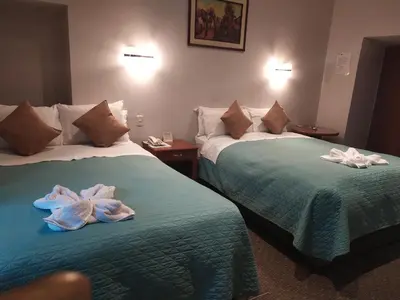 two beds in a hotel room with towels on them at HOTEL AMTALLPA San Blas Inn in Cusco