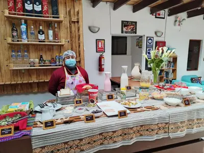 a person wearing a mask standing behind a table with food at HOTEL AMTALLPA San Blas Inn in Cusco