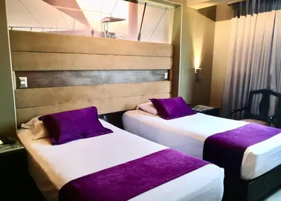 two beds in a hotel room with purple pillows at Hotel Las Lomas in Lima