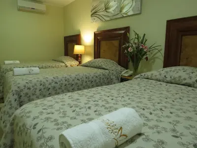 two beds in a hotel room with flowers on them at Hotel Las Flores in Ica