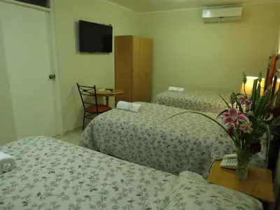 a hotel room with two beds and a television at Hotel Las Flores in Ica