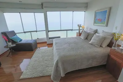 a bedroom with a large bed and a chair at Oceanfront Penthouse in Miraflores in Lima