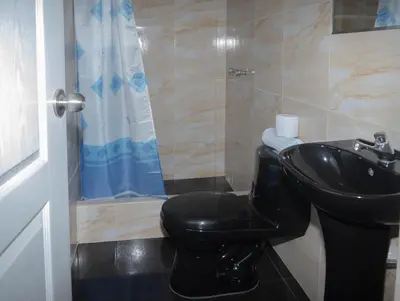 a bathroom with a black toilet and a sink at Hostal Sueños in Lima
