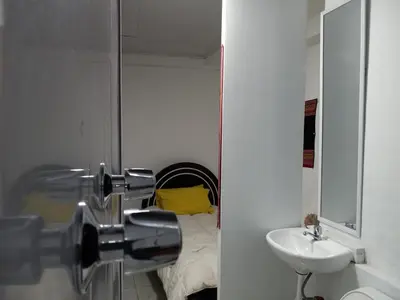 a bathroom with a sink and a mirror and a bed at Posada Azul Cusco in Cusco
