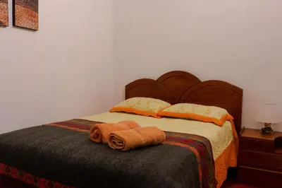 a bed with a wooden headboard and two towels on it at Posada Azul Cusco in Cusco
