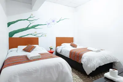 two beds in a room with a painting on the wall at Magic Cusco in Cusco