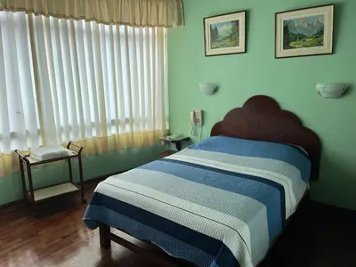 a bedroom with a bed with a blue and white blanket at Hotel SKY in Lima