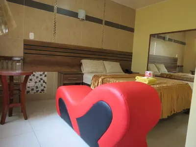 a bedroom with a red and blue chair in front of a bed at HOTEL ESTRELLA in Lima