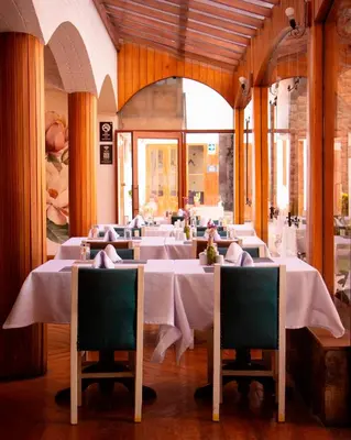 a row of tables in a restaurant with white table cloth at Hotel Monasterio San Pedro in Cusco