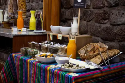 a table with bowls of food and drinks on it at Hotel Monasterio San Pedro in Cusco