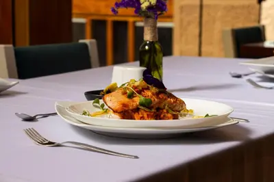 a plate of food on a table with a bottle of wine at Hotel Monasterio San Pedro in Cusco