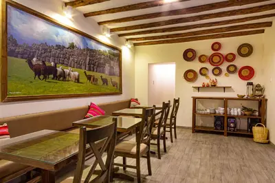 a restaurant with tables and chairs and a large painting on the wall at Luna House Cusco in Cusco
