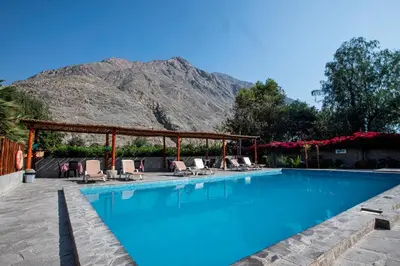 a swimming pool with chairs and a mountain in the background at La Confianza Hotel in Lunahuaná