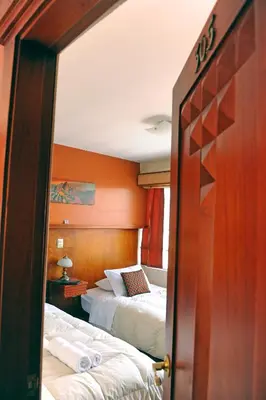 a hotel room with two beds and a mirror at Hotel Waynapicchu in Cusco