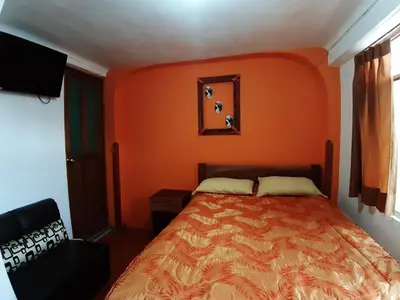 a bed in a room with an orange wall at Hatun Quilla in Cusco