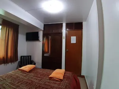 a bedroom with a bed with two orange pillows on it at Hatun Quilla in Cusco