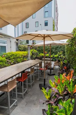 a table and chairs with an umbrella and some plants at Xima Lima San Isidro in Lima