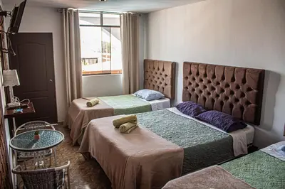 a room with three beds and a table and a window at Huacachina Desert House in Ica