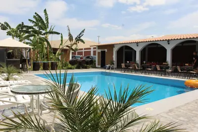 a pool with a table and chairs next to a building at Huacachina Desert House in Ica