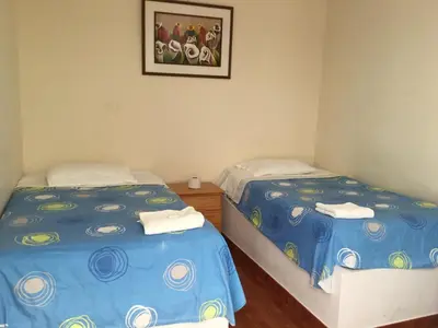 a room with two beds and a picture on the wall at Paracas Backpackers House in Paracas