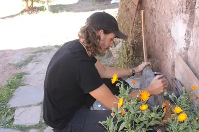 a man in a black shirt planting flowers at Maison Fortaleza in Cusco