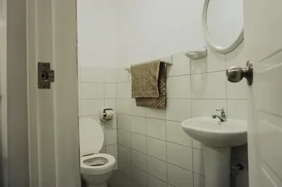 a white bathroom with a toilet and a sink at Hospedaje El Velero in Paracas