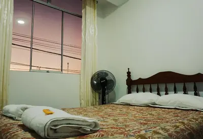 a bedroom with a bed with a blanket and a fan at Hospedaje El Velero in Paracas