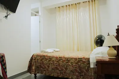 a bedroom with a bed and a window with curtains at Hospedaje El Velero in Paracas