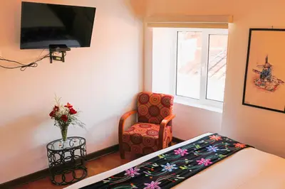 a bedroom with a bed and a chair and a tv at Auka Boutique San Blas in Cusco