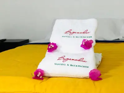 a towel on a bed with pink flowers on it at BUGANVILIA in Paracas