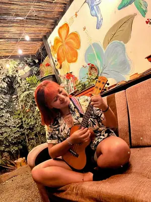 a woman sitting on a couch playing a guitar at Samanai Wasi in Lima