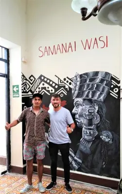 two men are standing in front of a sign at Samanai Wasi in Lima